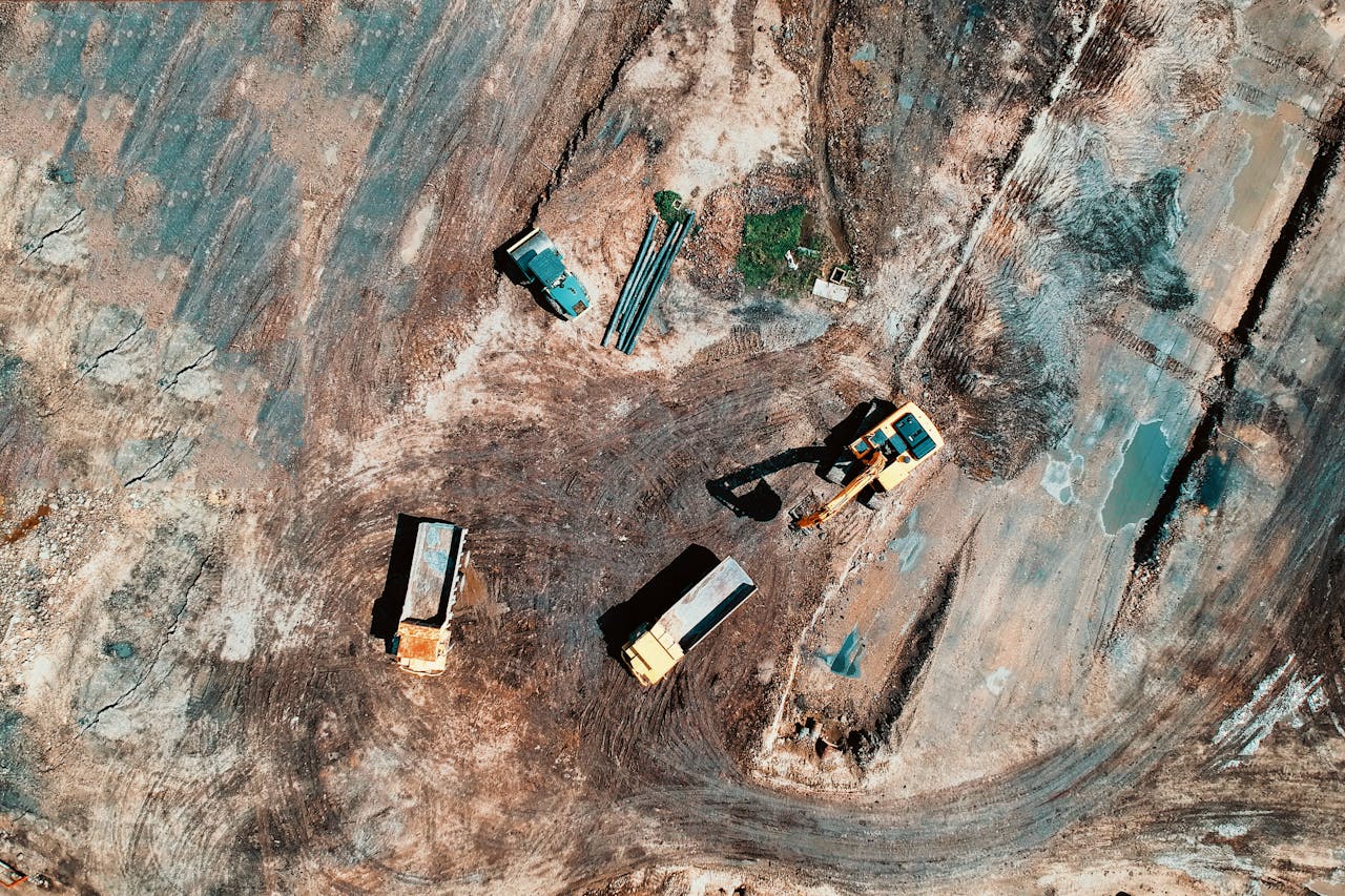 Aerial view of a construction site featuring trucks and excavation equipment in a barren landscape.