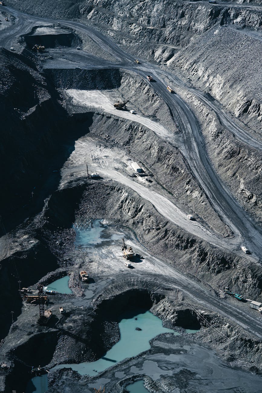 Aerial shot of an expansive open-pit mining operation with industrial machinery and mining layers visible.